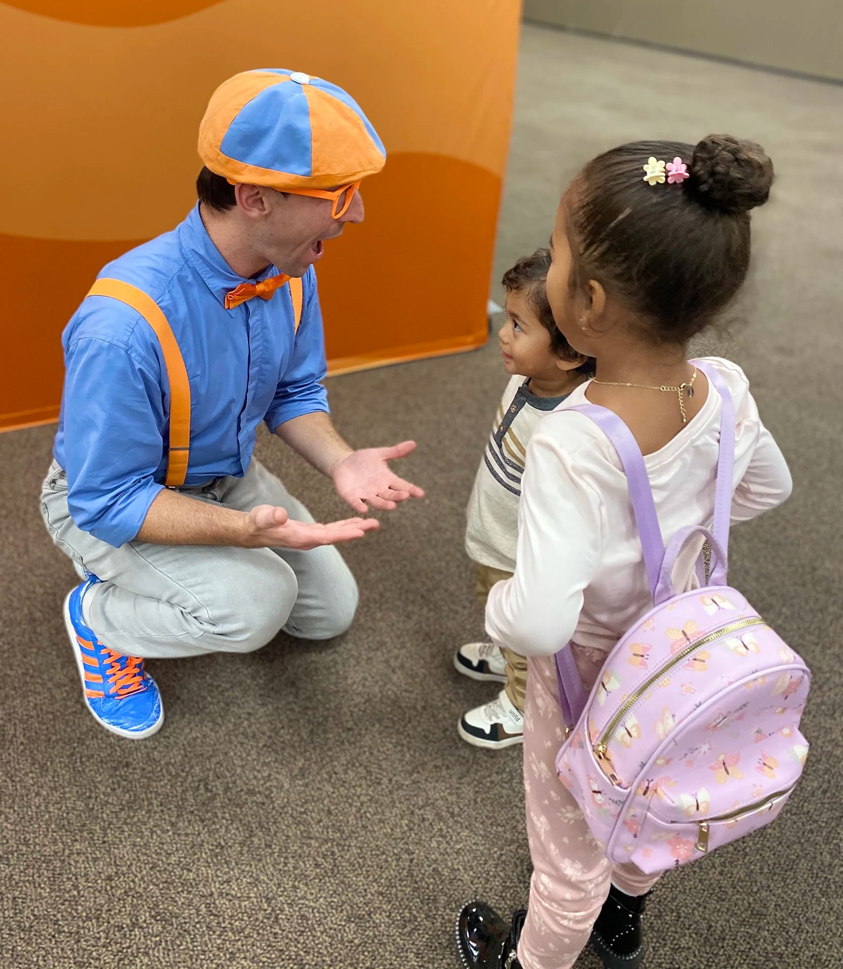 Blippi kneeling down to 2 kids.
