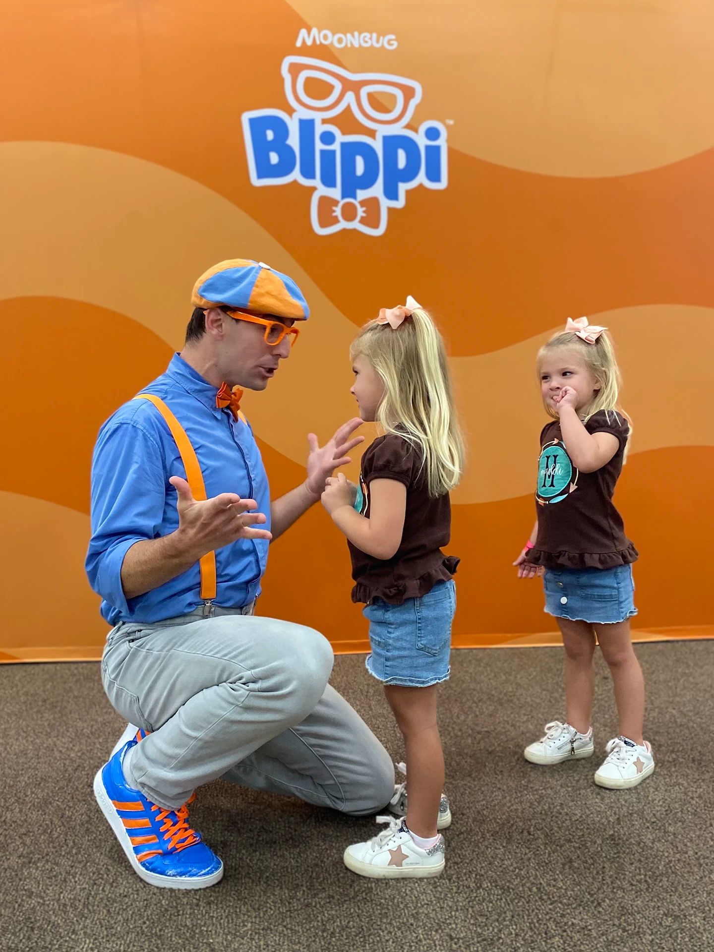 Blippi kneeling down to 2 kids.